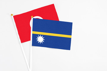 Nauru and Tunisia stick flags on white background. High quality fabric, miniature national flag. Peaceful global concept.White floor for copy space.