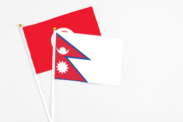 Obraz premium Nepal and Tunisia stick flags on white background. High quality fabric, miniature national flag. Peaceful global concept.White floor for copy space.
