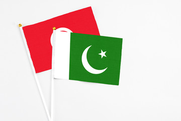 Pakistan and Tunisia stick flags on white background. High quality fabric, miniature national flag. Peaceful global concept.White floor for copy space.