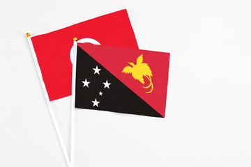 Papua New Guinea and Tunisia stick flags on white background. High quality fabric, miniature national flag. Peaceful global concept.White floor for copy space.