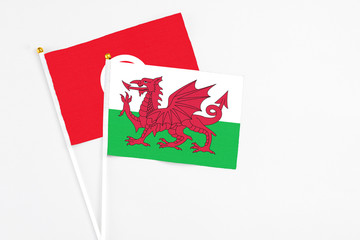 Wales and Tunisia stick flags on white background. High quality fabric, miniature national flag. Peaceful global concept.White floor for copy space.