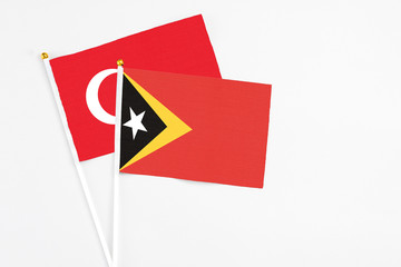 East Timor and Turkey stick flags on white background. High quality fabric, miniature national flag. Peaceful global concept.White floor for copy space.