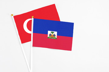 Haiti and Turkey stick flags on white background. High quality fabric, miniature national flag. Peaceful global concept.White floor for copy space.