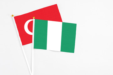 Nigeria and Turkey stick flags on white background. High quality fabric, miniature national flag. Peaceful global concept.White floor for copy space.