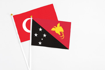 Papua New Guinea and Turkey stick flags on white background. High quality fabric, miniature national flag. Peaceful global concept.White floor for copy space.