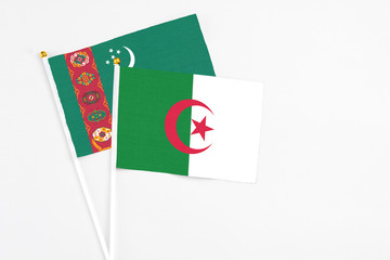 Algeria and Turkmenistan stick flags on white background. High quality fabric, miniature national flag. Peaceful global concept.White floor for copy space.