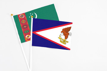 American Samoa and Turkmenistan stick flags on white background. High quality fabric, miniature national flag. Peaceful global concept.White floor for copy space.