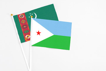 Djibouti and Turkmenistan stick flags on white background. High quality fabric, miniature national flag. Peaceful global concept.White floor for copy space.