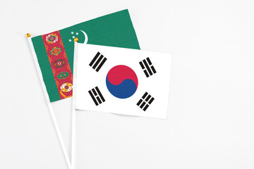 South Korea and Turkmenistan stick flags on white background. High quality fabric, miniature national flag. Peaceful global concept.White floor for copy space.