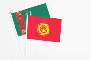 Kyrgyzstan and Turkmenistan stick flags on white background. High quality fabric, miniature national flag. Peaceful global concept.White floor for copy space.