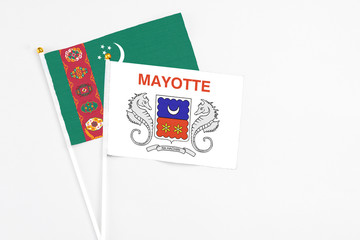 Mayotte and Turkmenistan stick flags on white background. High quality fabric, miniature national flag. Peaceful global concept.White floor for copy space.