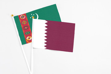 Qatar and Turkmenistan stick flags on white background. High quality fabric, miniature national flag. Peaceful global concept.White floor for copy space.