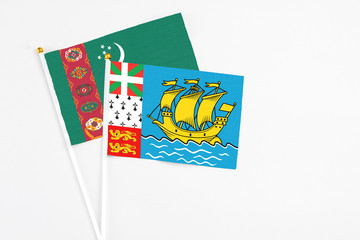 Saint Pierre And Miquelon and Turkmenistan stick flags on white background. High quality fabric, miniature national flag. Peaceful global concept.White floor for copy space.