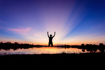 Freedom-young man is jumping at lake with sunset sky