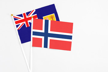 Fototapeta premium Norway and Turks And Caicos Islands stick flags on white background. High quality fabric, miniature national flag. Peaceful global concept.White floor for copy space.