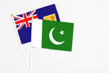 Pakistan and Turks And Caicos Islands stick flags on white background. High quality fabric, miniature national flag. Peaceful global concept.White floor for copy space.