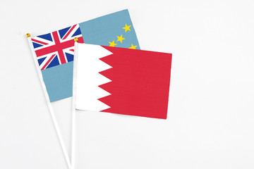 Bahrain and Tuvalu stick flags on white background. High quality fabric, miniature national flag. Peaceful global concept.White floor for copy space.