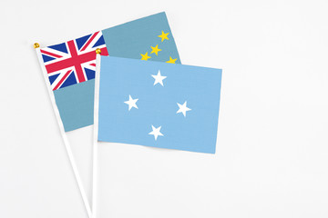 Micronesia and Tuvalu stick flags on white background. High quality fabric, miniature national flag. Peaceful global concept.White floor for copy space.