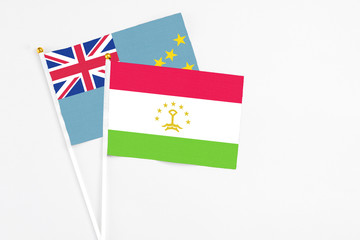 Tajikistan and Tuvalu stick flags on white background. High quality fabric, miniature national flag. Peaceful global concept.White floor for copy space.