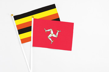 Isle Of Man and Uganda stick flags on white background. High quality fabric, miniature national...
