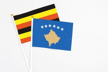 Kosovo and Uganda stick flags on white background. High quality fabric, miniature national flag. Peaceful global concept.White floor for copy space.