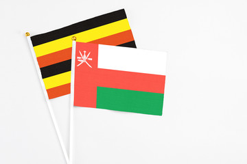 Oman and Uganda stick flags on white background. High quality fabric, miniature national flag. Peaceful global concept.White floor for copy space.