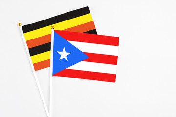 Puerto Rico and Uganda stick flags on white background. High quality fabric, miniature national flag. Peaceful global concept.White floor for copy space.