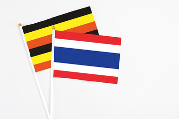 Thailand and Uganda stick flags on white background. High quality fabric, miniature national flag. Peaceful global concept.White floor for copy space.