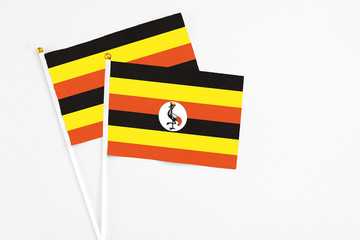 Fototapeta premium Uganda and Uganda stick flags on white background. High quality fabric, miniature national flag. Peaceful global concept.White floor for copy space.