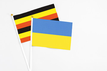 Ukraine and Uganda stick flags on white background. High quality fabric, miniature national flag. Peaceful global concept.White floor for copy space.