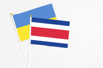 Costa Rica and Ukraine stick flags on white background. High quality fabric, miniature national flag. Peaceful global concept.White floor for copy space.