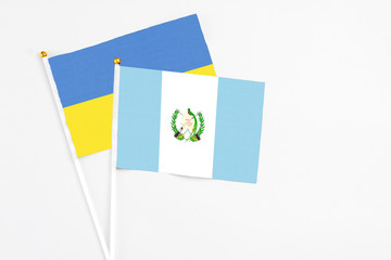 Guatemala and Ukraine stick flags on white background. High quality fabric, miniature national flag. Peaceful global concept.White floor for copy space.