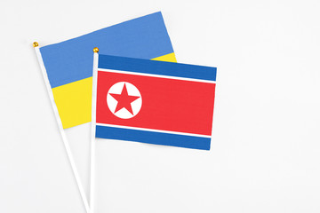 North Korea and Ukraine stick flags on white background. High quality fabric, miniature national flag. Peaceful global concept.White floor for copy space.