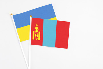 Fototapeta premium Mongolia and Ukraine stick flags on white background. High quality fabric, miniature national flag. Peaceful global concept.White floor for copy space.