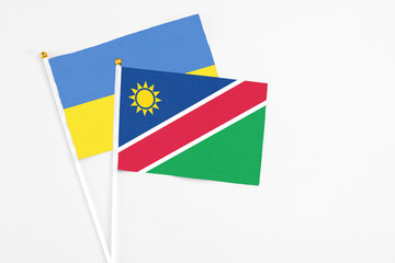 Namibia and Ukraine stick flags on white background. High quality fabric, miniature national flag. Peaceful global concept.White floor for copy space.