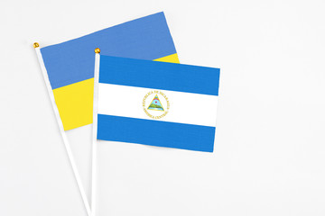 Nicaragua and Ukraine stick flags on white background. High quality fabric, miniature national flag. Peaceful global concept.White floor for copy space.