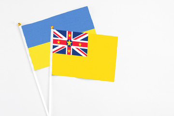 Niue and Ukraine stick flags on white background. High quality fabric, miniature national flag. Peaceful global concept.White floor for copy space.