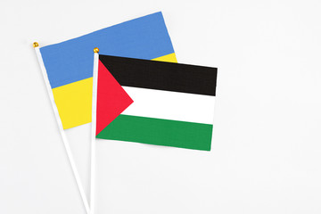 Palestine and Ukraine stick flags on white background. High quality fabric, miniature national flag. Peaceful global concept.White floor for copy space.