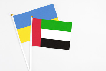 United Arab Emirates and Ukraine stick flags on white background. High quality fabric, miniature national flag. Peaceful global concept.White floor for copy space.