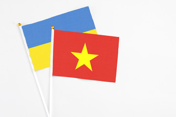 Vietnam and Ukraine stick flags on white background. High quality fabric, miniature national flag. Peaceful global concept.White floor for copy space.