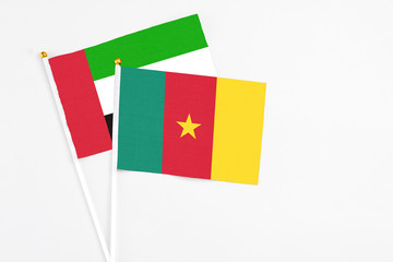 Cameroon and United Arab Emirates stick flags on white background. High quality fabric, miniature national flag. Peaceful global concept.White floor for copy space.