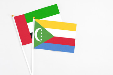 Comoros and United Arab Emirates stick flags on white background. High quality fabric, miniature national flag. Peaceful global concept.White floor for copy space.
