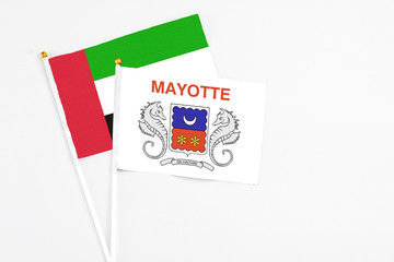 Mayotte and United Arab Emirates stick flags on white background. High quality fabric, miniature national flag. Peaceful global concept.White floor for copy space.