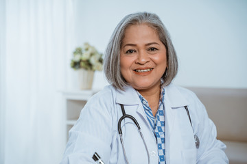 The senior doctor smiled wearing a uniform in the office room