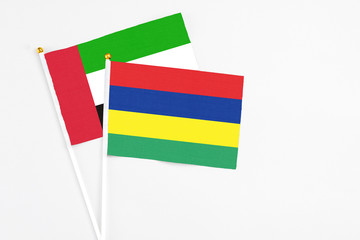 Mauritius and United Arab Emirates stick flags on white background. High quality fabric, miniature national flag. Peaceful global concept.White floor for copy space.