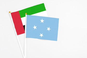 Micronesia and United Arab Emirates stick flags on white background. High quality fabric, miniature national flag. Peaceful global concept.White floor for copy space.