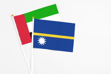 Nauru and United Arab Emirates stick flags on white background. High quality fabric, miniature national flag. Peaceful global concept.White floor for copy space.
