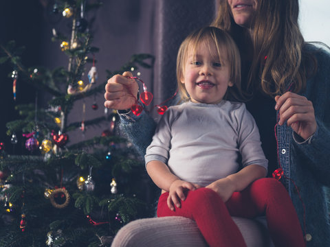 Mother and toddler with heart shaped lights by christmas tree