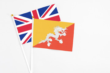 Bhutan and United Kingdom stick flags on white background. High quality fabric, miniature national flag. Peaceful global concept.White floor for copy space.