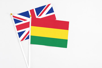 Bolivia and United Kingdom stick flags on white background. High quality fabric, miniature national flag. Peaceful global concept.White floor for copy space.